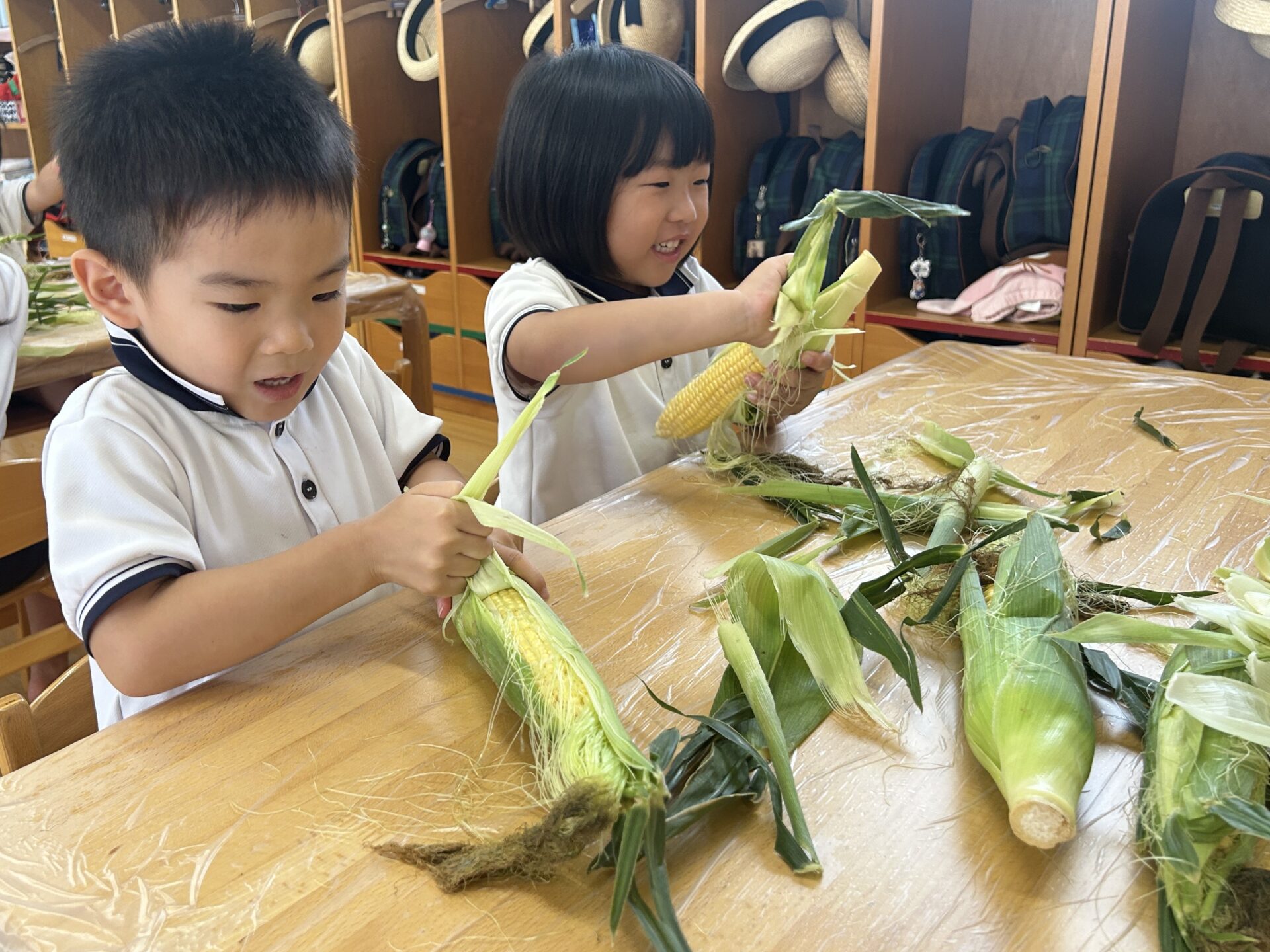 7月の食育活動～とうもろこしの皮むき～ポピンズエデュケア