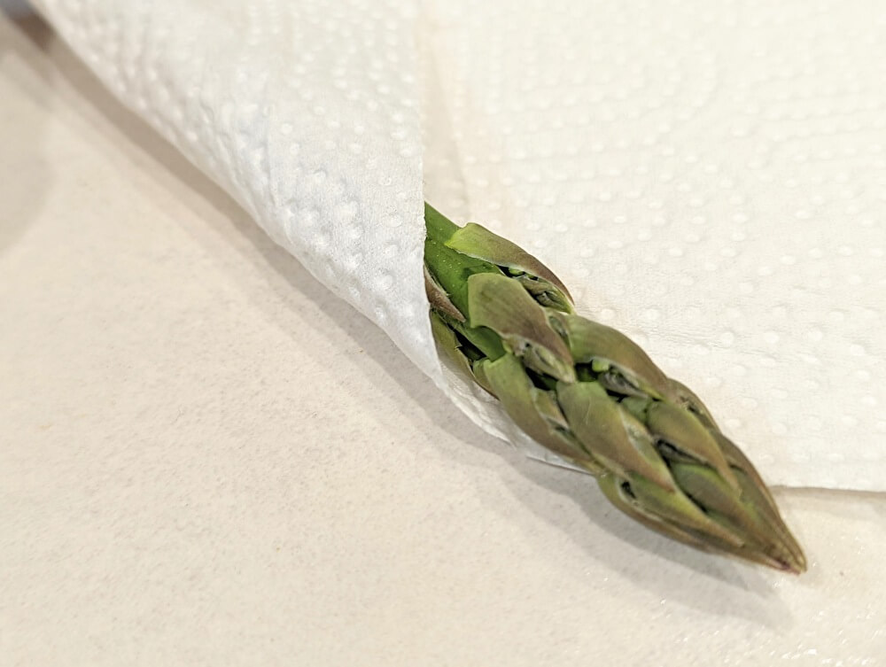 アスパラガスを冷蔵保存する際の手順を紹介します。 1.アスパラの切り口側を少しカットする 2.コップに水を入れる 3.コップにアスパラを入れて袋をかけて冷蔵庫に入れるこれだけでコップに入れた水をアスパラガスが吸っていくことで、乾燥を防いで1週間は鮮度の良い状態