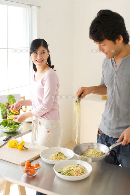 モダンなキッチンで一緒に料理をして美しい笑顔のカップル無料写真