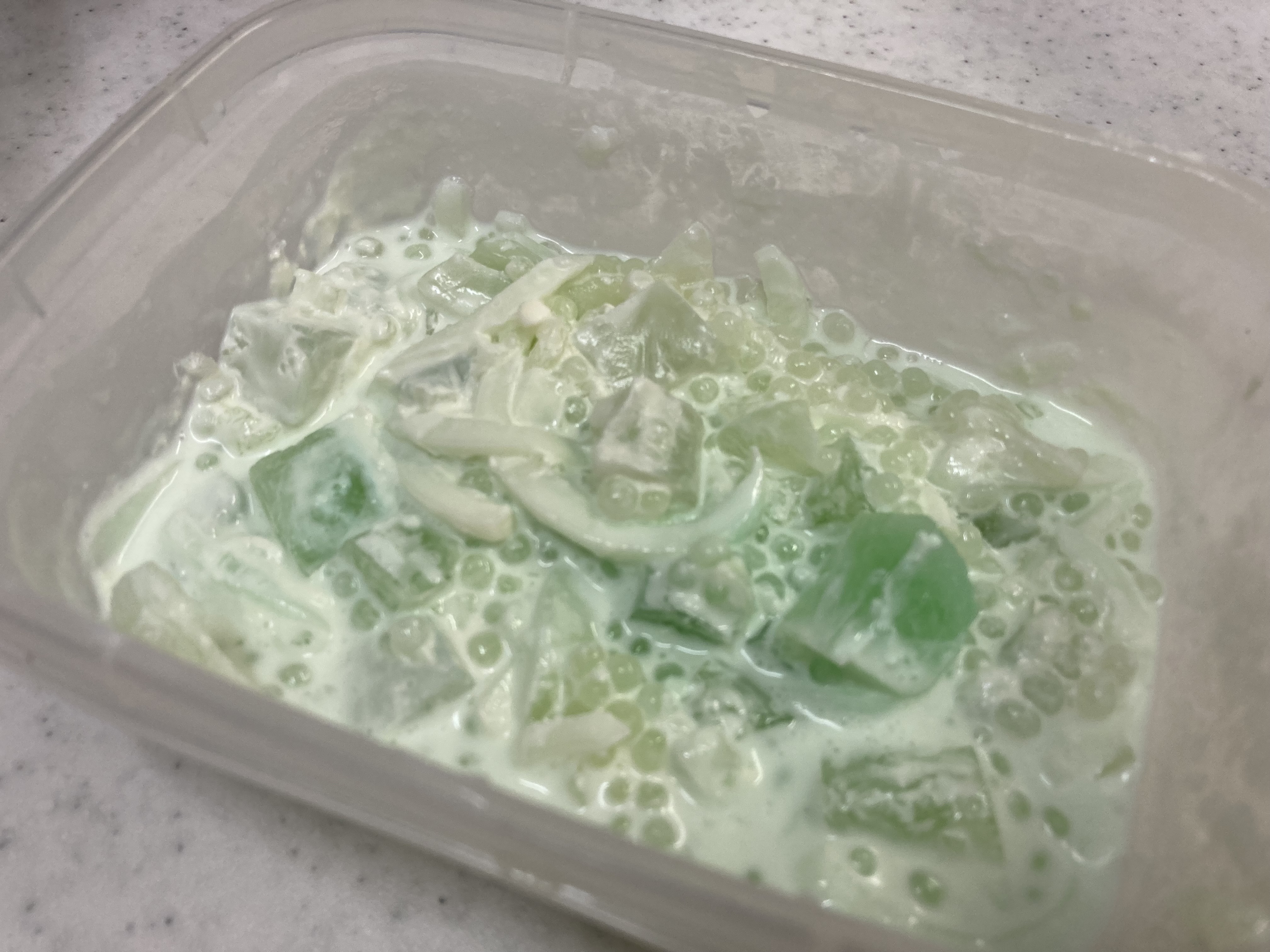 ブコパンダンは、ゼリーとパンダンジュースにサゴパールと細かく刻んだココナッツの果肉をクリームまたはミルクで混ぜた甘い食べ物です。コピースペースのあるガラスの白いテーブルの背景に添えて。Premium写真